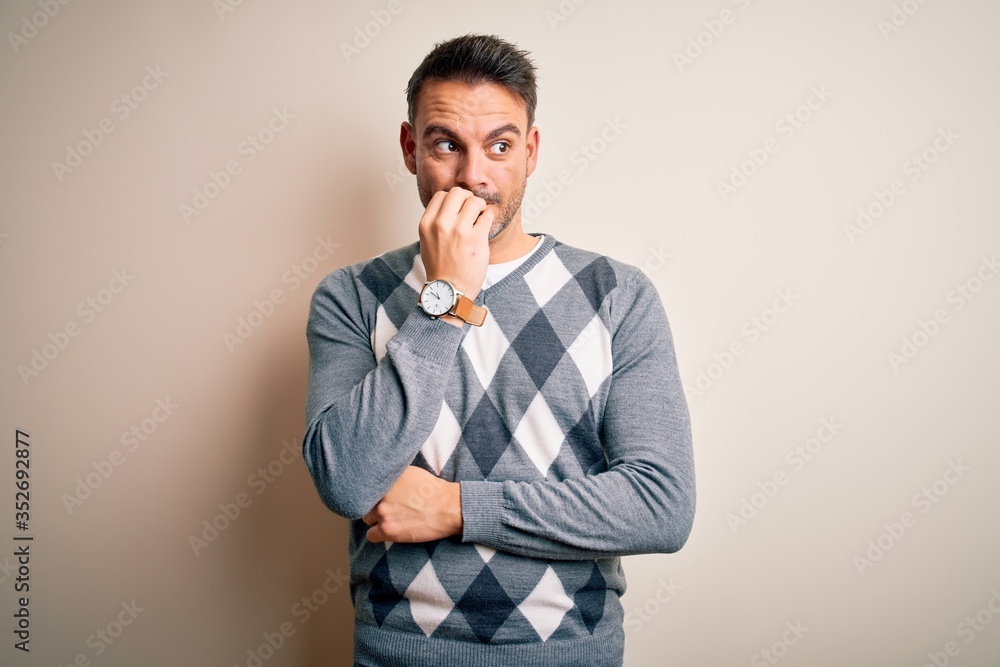 Young handsome man wearing casual sweater standing over isolated white background looking stressed and nervous with hands on mouth biting nails. Anxiety problem. Young handsome man wearing casual sweater standing over isolated white background looking stressed and nervous with hands on mouth biting nails. Anxiety problem.