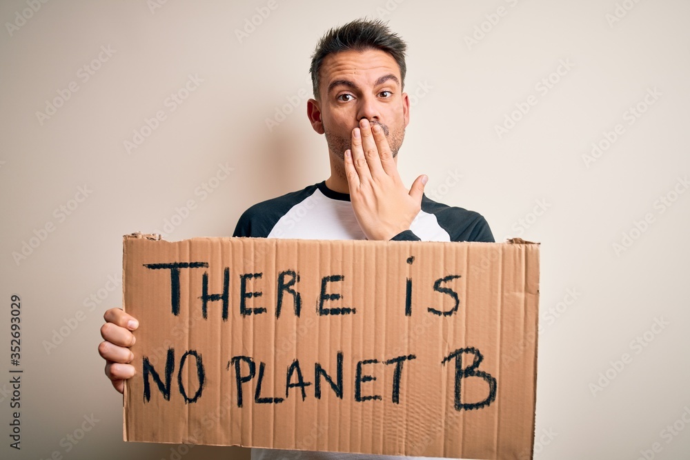 Young handsome man asking for environment holding banner with planet message cover mouth with hand shocked with shame for mistake, expression of fear, scared in silence, secret concept Young handsome man asking for environment holding banner with planet message cover mouth with hand shocked with shame for mistake, expression of fear, scared in silence, secret concept