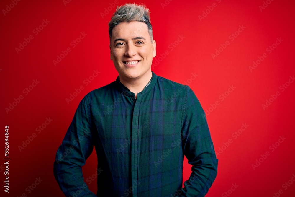 Obraz premium Young handsome modern man wearing elegant green shirt over red isolated background with a happy and cool smile on face. Lucky person.