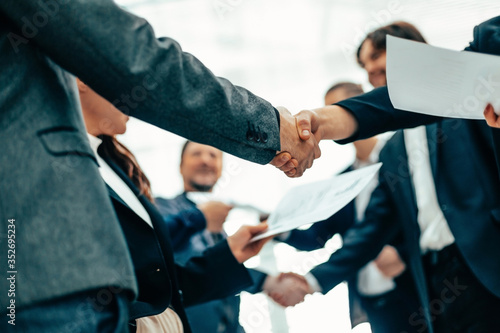 group of employees shaking hands at an office meeting. © yurolaitsalbert