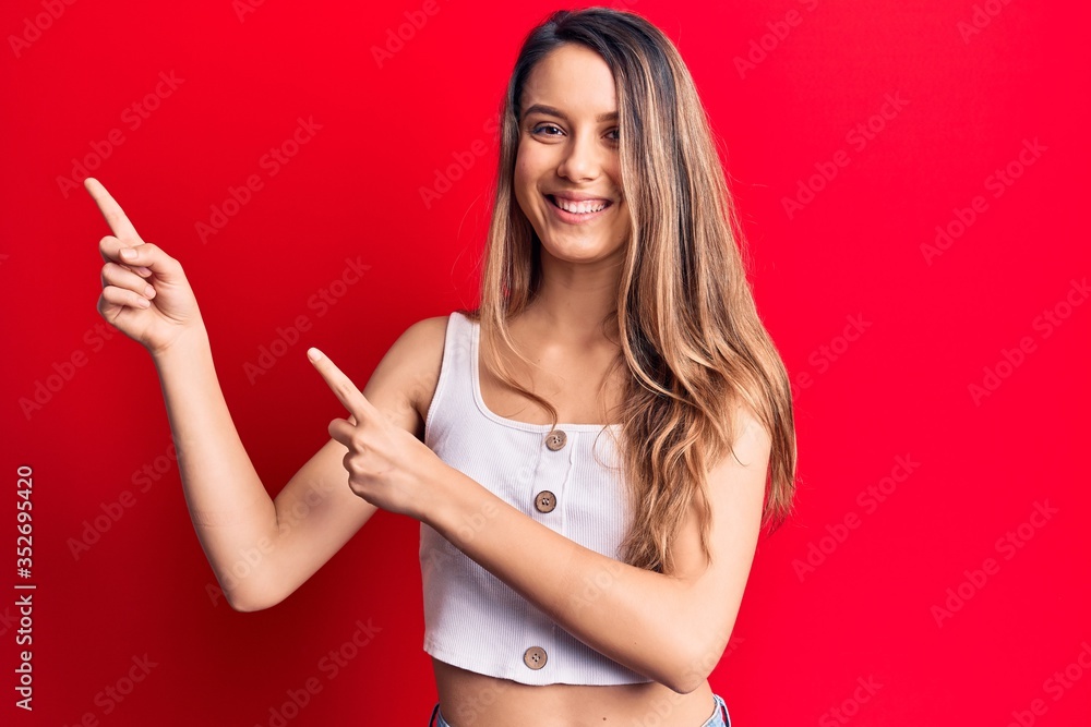 Young beautiful girl wearing casual sleeveless t-shirt smiling and looking at the camera pointing with two hands and fingers to the side. Young beautiful girl wearing casual sleeveless t-shirt smiling and looking at the camera pointing with two hands and fingers to the side.