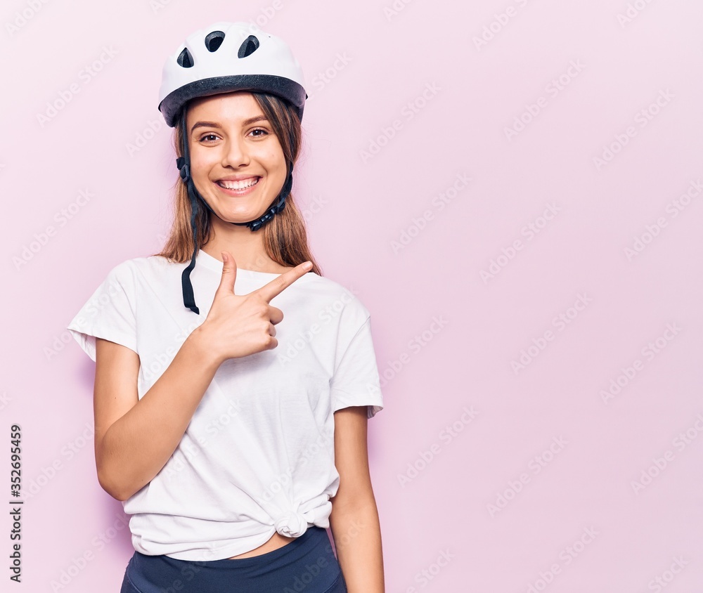 Young beautiful girl wearing bike helmet smiling cheerful pointing with hand and finger up to the side Young beautiful girl wearing bike helmet smiling cheerful pointing with hand and finger up to the side