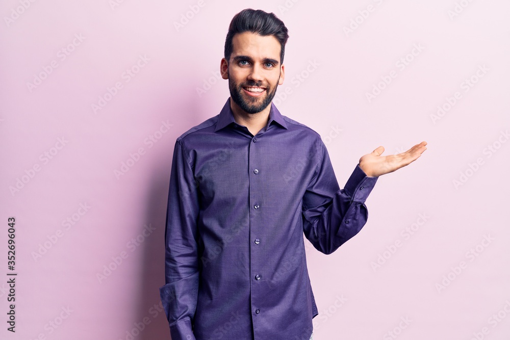 Young handsome man with beard wearing casual shirt smiling cheerful presenting and pointing with palm of hand looking at the camera. Young handsome man with beard wearing casual shirt smiling cheerful presenting and pointing with palm of hand looking at the camera.