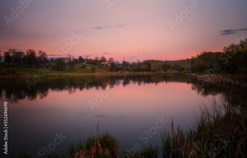 Amazing sunset view of scenic lake near medieval castle on the bank with reflection in the water and reeds on foreground. Svirzh, Ukraine. April 2020
