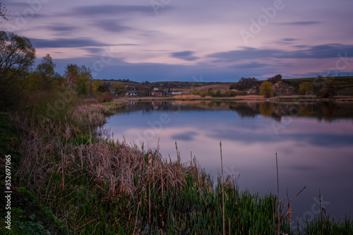 Amazing sunset view of scenic lake near medieval castle on the bank with reflection in the water and reeds on foreground. Svirzh  Ukraine. April 2020