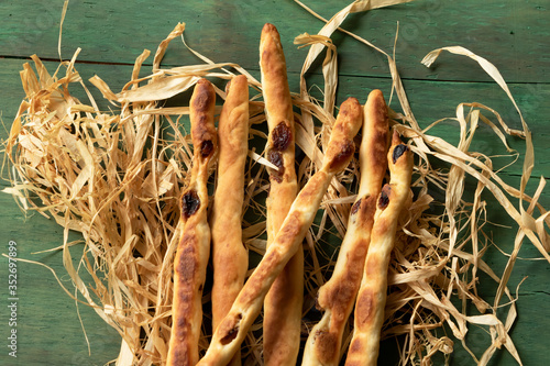 Breadsticks grissini with raisins on a green wood background.