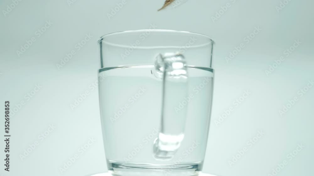 Poured with boiling water from the kettle into a glass cup and put spoon of granulated coffee, on white background. Closeup. The camera moves around. Slow motion. High speed camera Poured with boiling water from the kettle into a glass cup and put spoon of granulated coffee, on white background. Closeup. The camera moves around. Slow motion. High speed camera