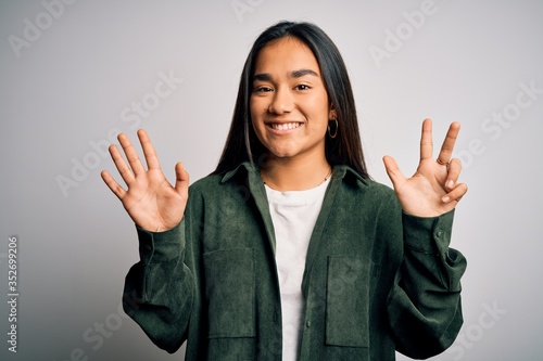 Young beautiful asian woman wearing casual shirt standing over isolated white background showing and pointing up with fingers number eight while smiling confident and happy.