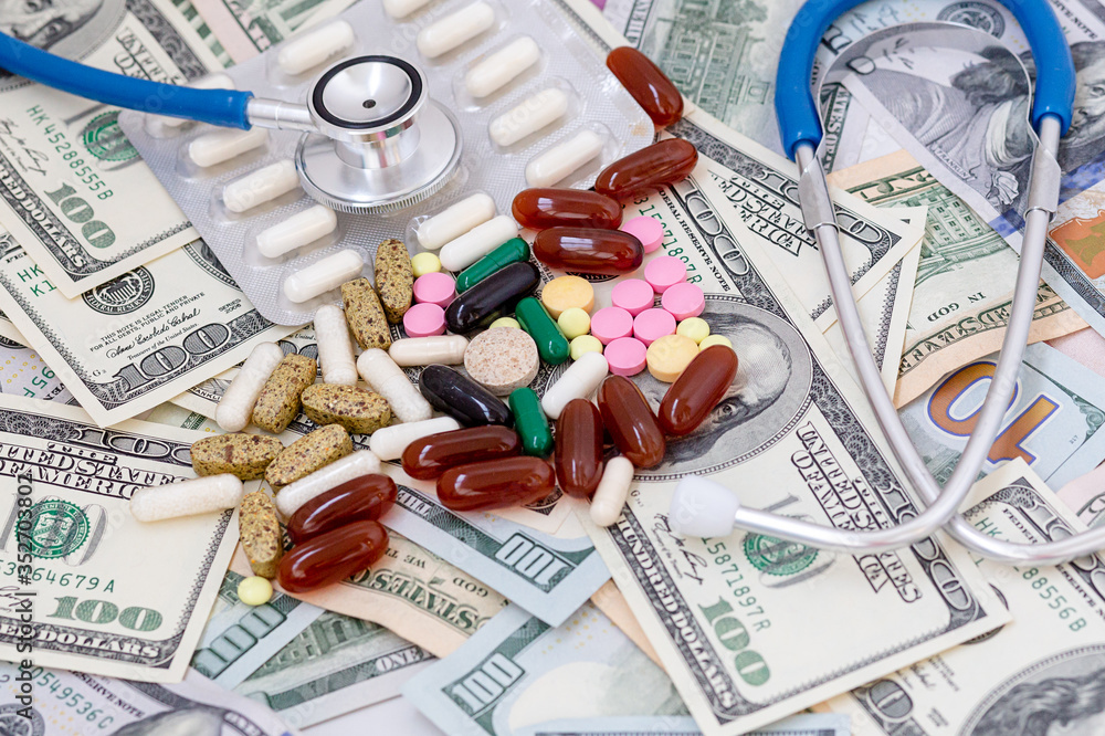 Pills of different colors on money background. Pills of different colors on money background.