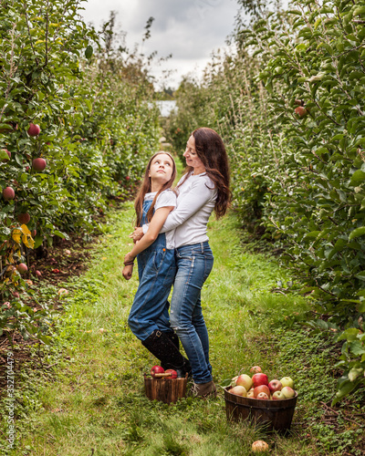 Portrait of little girl and beautiful mother in organic apple orchard happy and having fun. © olegmayorov