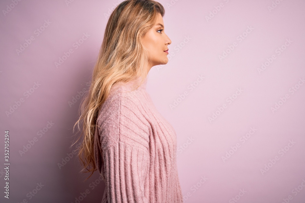 Young beautiful blonde woman wearing casual pink sweater over isolated background looking to side, relax profile pose with natural face with confident smile. Young beautiful blonde woman wearing casual pink sweater over isolated background looking to side, relax profile pose with natural face with confident smile.