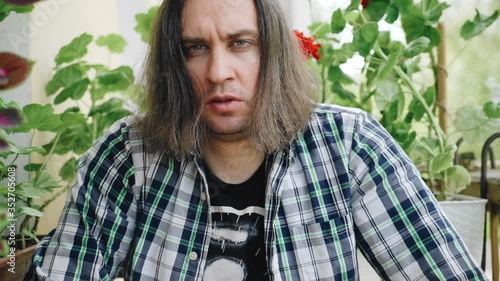 A man with long hair looks unkindly at the camera. Emotions on the face photo