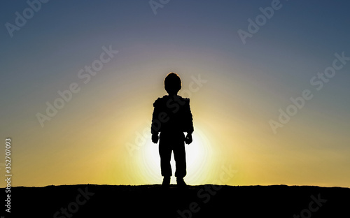 Kid looking at the sunset. Against light