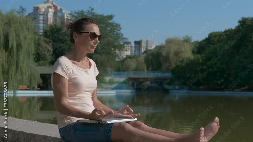Office worker by water. A woman with a laptop near a pond in a summer park. Digital nomads concept. Office worker by water. A woman with a laptop near a pond in a summer park. Digital nomads concept.