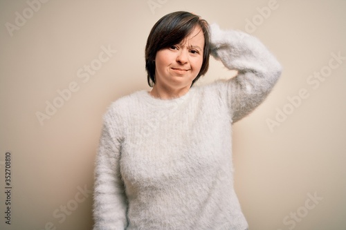 Young down syndrome woman standing over isolated background confuse and wonder about question. Uncertain with doubt, thinking with hand on head. Pensive concept. © Krakenimages.com