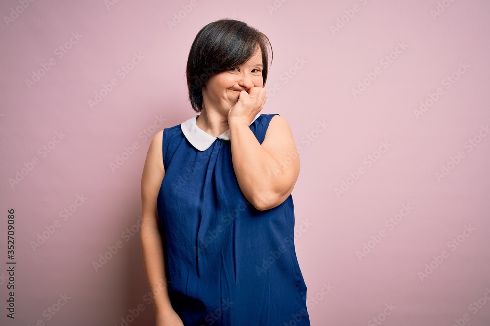 Young down syndrome woman wearing elegant shirt over pink background looking stressed and nervous with hands on mouth biting nails. Anxiety problem. Young down syndrome woman wearing elegant shirt over pink background looking stressed and nervous with hands on mouth biting nails. Anxiety problem.