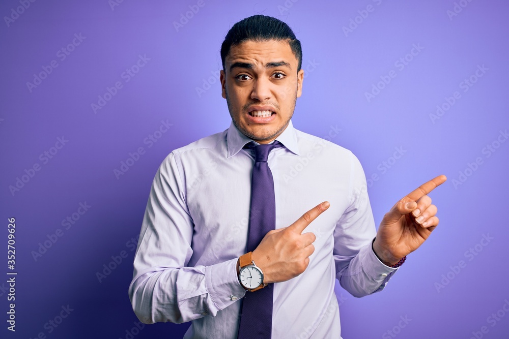 Young brazilian businessman wearing elegant tie standing over isolated purple background Pointing aside worried and nervous with both hands, concerned and surprised expression Young brazilian businessman wearing elegant tie standing over isolated purple background Pointing aside worried and nervous with both hands, concerned and surprised expression