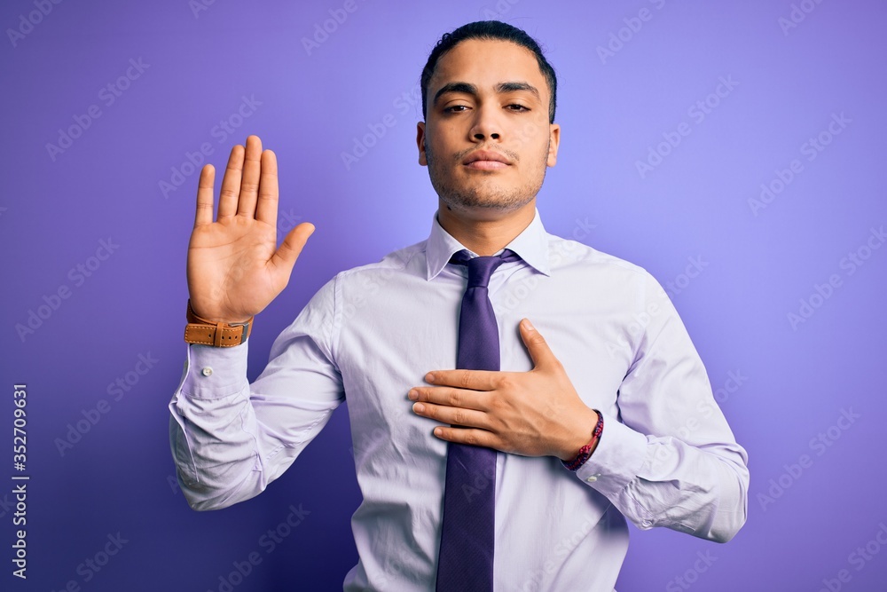 Young brazilian businessman wearing elegant tie standing over isolated purple background Swearing with hand on chest and open palm, making a loyalty promise oath Young brazilian businessman wearing elegant tie standing over isolated purple background Swearing with hand on chest and open palm, making a loyalty promise oath