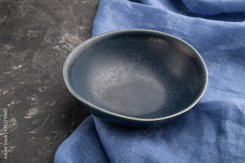 Empty blue ceramic bowl on black concrete background. Side view, close up.