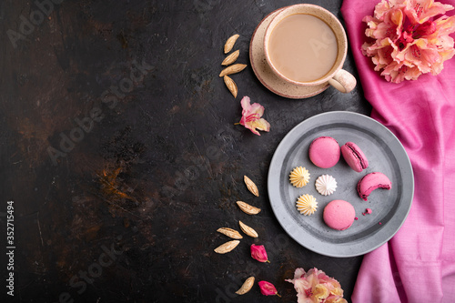 Purple macarons or macaroons cakes with cup of coffee on a black concrete background. Top view, copy space.