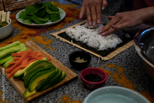 Preparation of vegan sushi. Cooked rice combined with rice vinegar and sugar and vegan ingredients are placed and seaweed is rolled with the help of bamboo mat