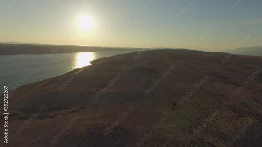 Aerial panning shot of road on landscape by sea against sky, drone flying from right to left during sunset - Razanac, Croatia Aerial panning shot of road on landscape by sea against sky, drone flying from right to left during sunset - Razanac, Croatia