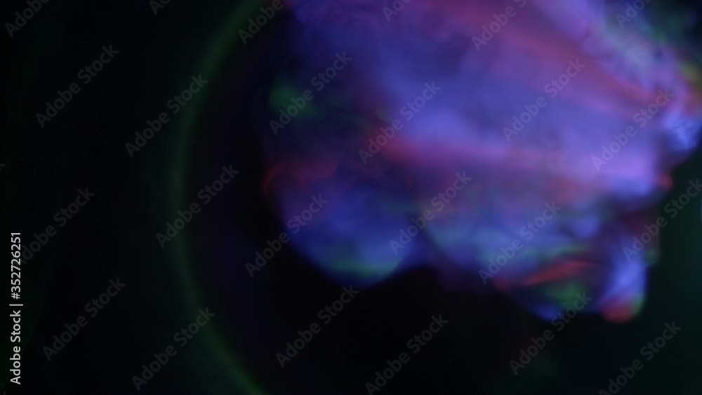 Bright multi-colored rays move in a stream of smoke and create beautiful flares on black background. Closeup. Slow motion. High speed camera Bright multi-colored rays move in a stream of smoke and create beautiful flares on black background. Closeup. Slow motion. High speed camera