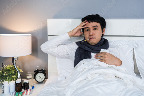 sick man is headache and using thermometer to checking his temperature in bed