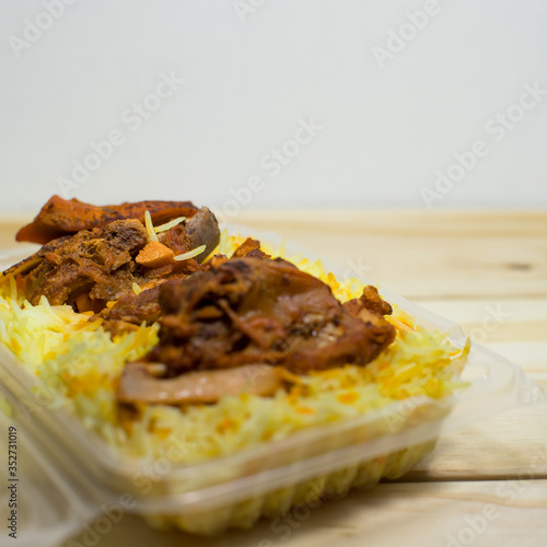 A plastic pack of lamb mandy rice on wood background. The best arabic food. Selective focus. photo