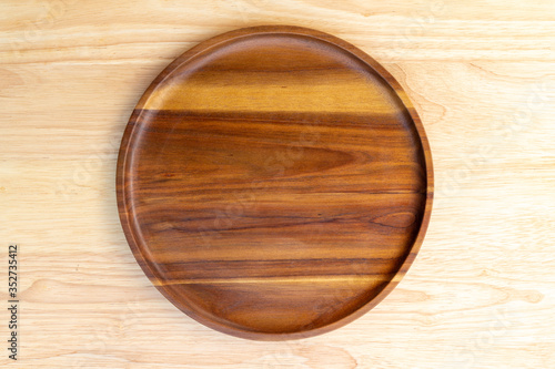 A round dish made of acacia wood and lacquered lacquer is placed on a rubber wood chopping block in the kitchen utensil concept.