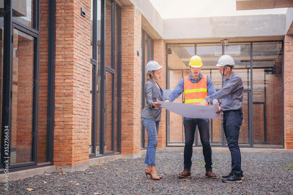 Structural engineer and architect working with blueprints discuss at the building structure, outdoor construction site