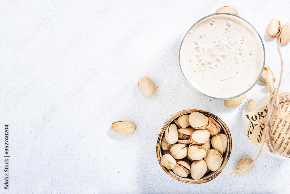 Vegan Pistachio nut milk in bottles, closeup, grey table background. Non dairy alternative milk. Healthy vegetarian food and drink concept. Copy space, top view Vegan Pistachio nut milk in bottles, closeup, grey table background. Non dairy alternative milk. Healthy vegetarian food and drink concept. Copy space, top view