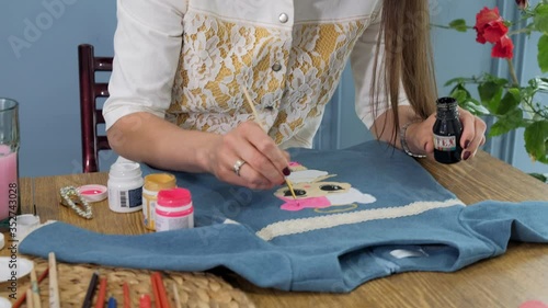 Designer painting on denim cloth. Making personal collection dresses for girls