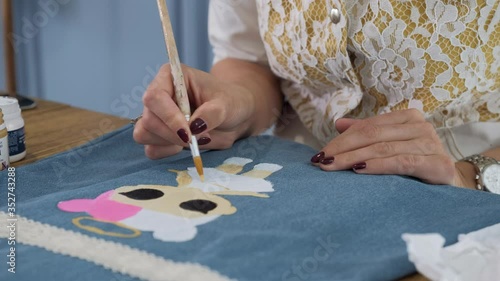 Designer painting on denim cloth. Making personal collection dresses for girls