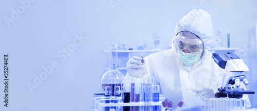 Science researcher in full protection equipment is experimenting and developing new vaccine to fight against virus in safety laboratory with copy space