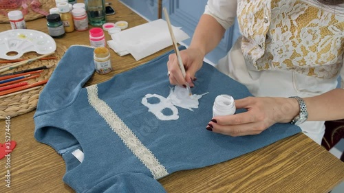 Designer painting on denim cloth. Making personal collection dresses for girls