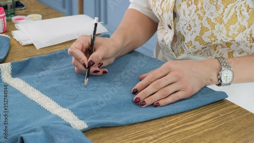 Designer painting on denim cloth. Making personal collection dresses for girls