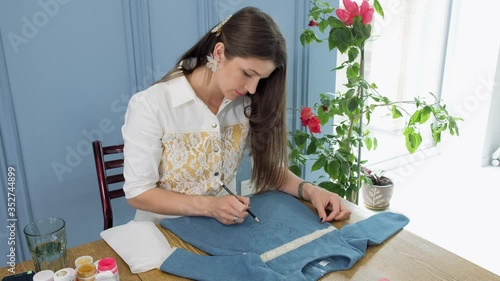 Designer painting on denim cloth. Making personal collection dresses for girls
