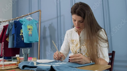 Designer painting on denim cloth. Making personal collection dresses for girls