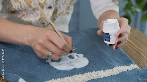 Designer painting on denim cloth. Making personal collection dresses for girls