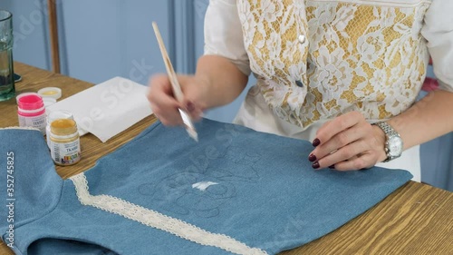 Designer painting on denim cloth. Making personal collection dresses for girls