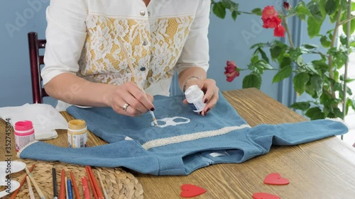 Designer painting on denim cloth. Making personal collection dresses for girls