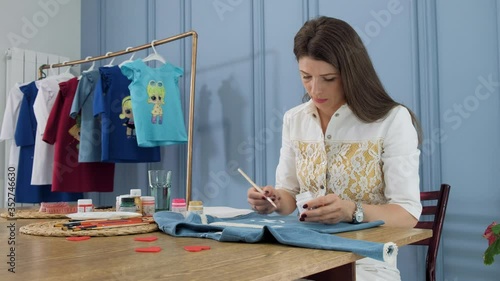 Designer painting on denim cloth. Making personal collection dresses for girls