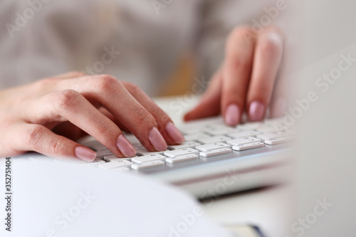 Female hands typing on silver keyboard using computer pc