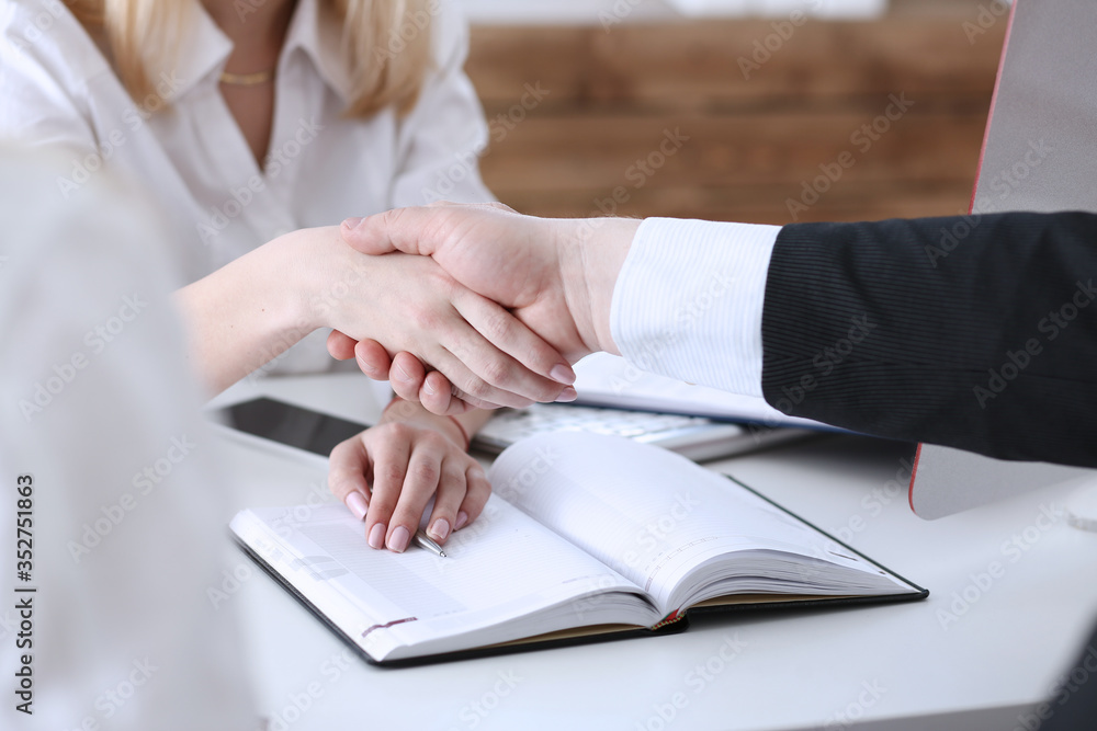 Businessman and woman shake hands as hello in office Businessman and woman shake hands as hello in office