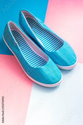 Casual summer footwear on pink and blue background. Women or teenage fashion, blue slipons. Urban shoes: flats, slip-on, sneaker. Flat lay, top view, copy space for text. Shopping and sale concept.