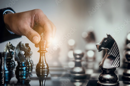 Foto Businessman moving chess piece and think strategic to win game