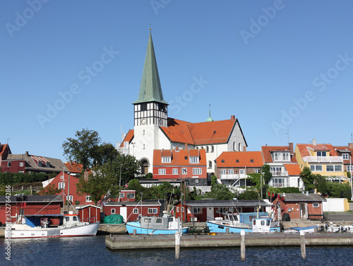 Fishing boats are in the harbor in the small town of Rønne on the Danish island of Bornholm in the Baltic Sea. In the background the historic white church of the city and several colorful houses.