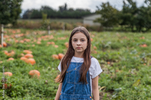 Fototapeta Naklejka Na Ścianę i Meble -  Cute little girl portrait in a pumpkin patch with blurry background.