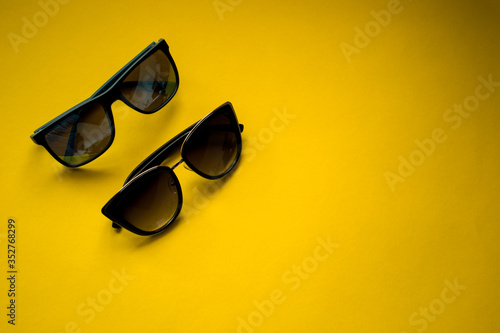 His and hers sunglasses on yellow background. Summertime, couple, beach concept